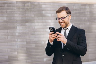 Businessman using mobile phone app for business matters next to office building