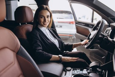 Businesswoman sitting in new car holding steering wheel in car dealership