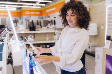Customer comparing electric toothbrushes in home appliance store, making purchasing decision for oral hygiene