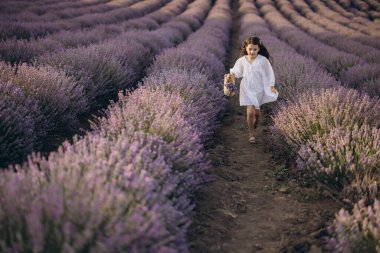 Young girl joyfully running through vibrant rows of lavender, embracing the enchanting scent and beauty of a sunlit summer day