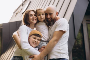 Smiling family embracing each other in front of their new sustainable home, expressing love, unity, and happiness