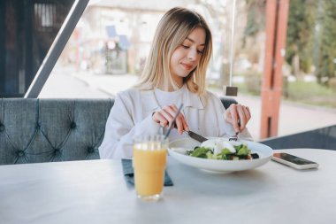 Businesswoman savoring a vibrant salad and refreshing orange juice for lunch in a stylish, modern restaurant, enjoying a moment of relaxation