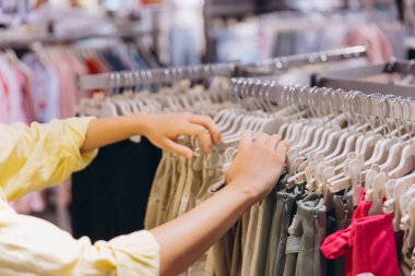 Woman browsing through clothing racks in a retail store, searching for the ideal outfit among a variety of stylish garments and apparel