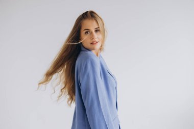 Studio portrait featuring a young blonde businesswoman in a stylish blue suit, showcasing flowing hair against a clean white background