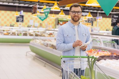 Customer writing shopping list while buying food in grocery store