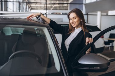 Saleswoman assisting a customer in selecting a new car within a modern dealership showroom, highlighting features and options available