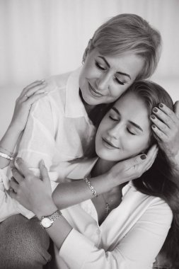 Mother and daughter hugging each other, with closed eyes, enjoying a moment of tenderness and complicity