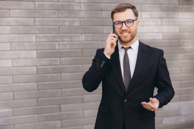 Businessman smiling while using mobile phone, wearing suit and tie