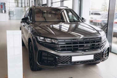 Modern gray suv parked on tiled floor of car dealership, reflecting bright light on polished hood, showcasing luxury and style