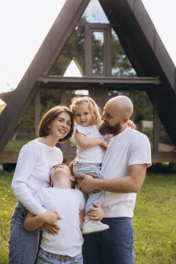 Smiling family embracing each other, enjoying their time together in the garden of their new a frame house