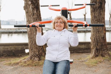 Elderly woman exercising on outdoor gym equipment, promoting active aging and healthy lifestyle