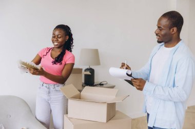 Happy African American couple unpacking boxes and organizing belongings in their bright, modern apartment, embracing new beginnings together