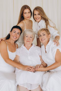 Four generations of women embracing one another, radiating love, care, and support while showcasing their strong family bond and connection