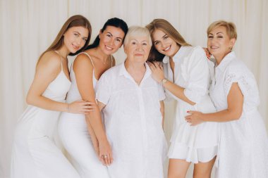 Five women of different generations posing together in white dresses, representing family bonds and togetherness