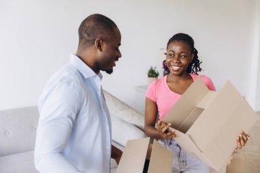 Smiling couple unpacking their belongings from cardboard boxes, joyfully settling into their new home and embracing fresh beginnings