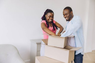 Smiling couple unpacking their belongings from cardboard boxes, enjoying the excitement of moving into their bright, new home together
