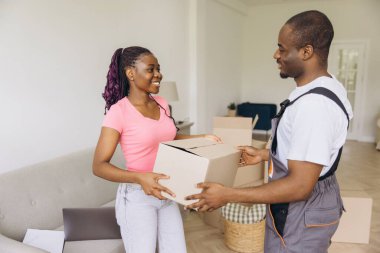 Professional African American movers assisting a homeowner with a cardboard box, ensuring a smooth and efficient moving process