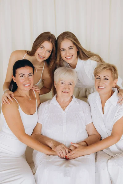 Four generations of women smiling and holding hands, representing family bonds and togetherness