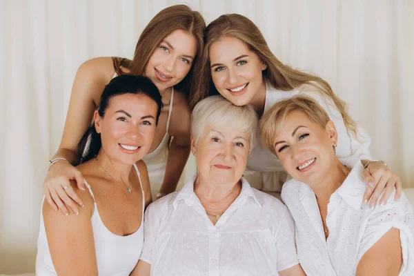 Grandmother, daughters and granddaughters hugging and smiling, representing family bonds and different age generations