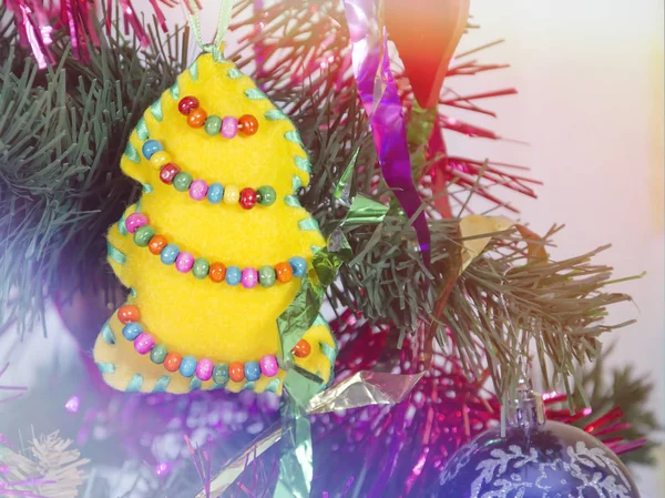 Мягкая игрушка в виде желтой елки с бисером на новогодней елке — стоковое фото