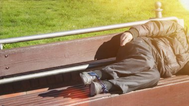 Zavallı evsiz adam ya da mülteci ahşap bankta uyuyor. 