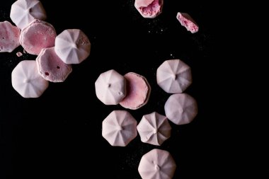Pembe Meringues siyah yüzey üzerine pudra şekeri ile. Şekerlemeler.
