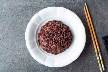Siyah pirinç beyaz tabakta yemek çubukları ile pişirilir. Geleneksel organik gıda.
