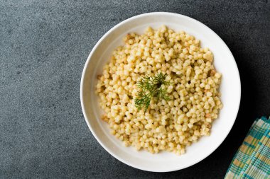 Kuskus beyaz tabak içinde servis dereotu ile pişmiş / Türk Kuskus. Geleneksel organik gıda.