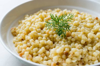 Kuskus beyaz tabak içinde servis dereotu ile pişmiş / Türk Kuskus. Geleneksel organik gıda.