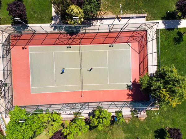 空中无人机观看网球场在花园与球员打网球 体育在城市 — 图库照片