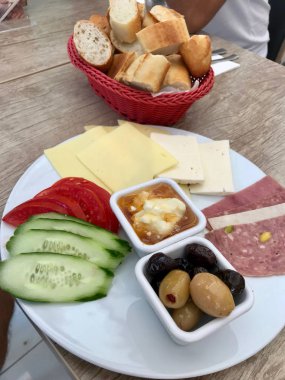 Türk kahvaltı tabağı bal, tereyağı krema (Kaymak), peynir, salatalık dilimleri, zeytin, jambon ve domates. Geleneksel gıda.