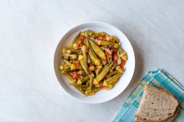 Domates ve soğan dilimleri ile yemek bamya yemek / Bamya. Geleneksel organik gıda.