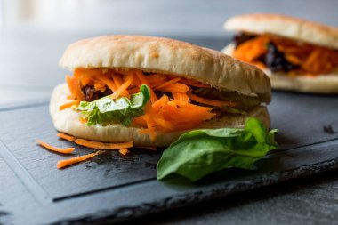 Vegan / Vejetaryen pide ekmek Bun sandviç Tayvan'ın Gua Bao havuç dilimleri ve yeşillik Asya ile. Geleneksel organik gıda.