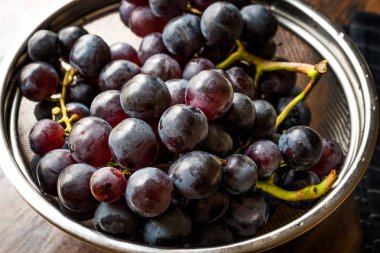 Metal kevgir içinde kırmızı üzüm demet. Organik gıda.