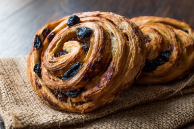 Danimarka tarçınlı üzümlü rulo sarmal / Almanca pasta Schnecken çuval üzerinde. Geleneksel gıda.
