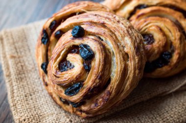 Danimarka tarçınlı üzümlü rulo sarmal / Almanca pasta Schnecken çuval üzerinde. Geleneksel gıda.