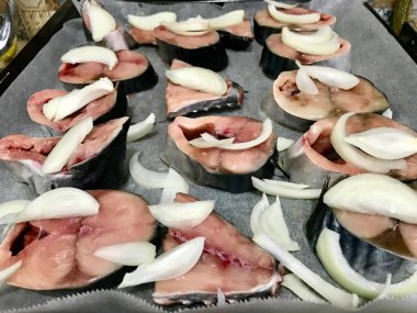 Yarım kesilmiş ham palamut Balık Fırında fırın tepsisi hazır soğan dilimlerle fileto. Organik su ürünleri.