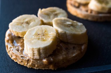 Bulgur pirinç kek dilimlenmiş muz ve fıstık ezmesi ile / kraker yuvarlak. Organik sağlıklı atıştırmalıklar.