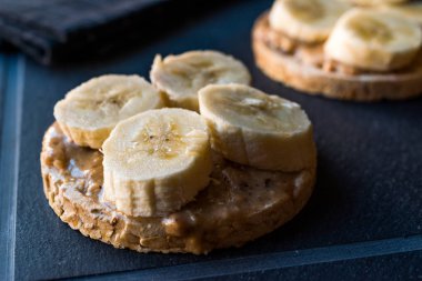 Bulgur pirinç kek dilimlenmiş muz ve fıstık ezmesi ile / kraker yuvarlak. Organik sağlıklı atıştırmalıklar.