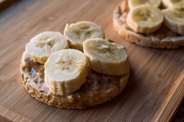 Bulgur pirinç kek dilimlenmiş muz ve fıstık ezmesi ile / kraker yuvarlak. Organik sağlıklı atıştırmalıklar.