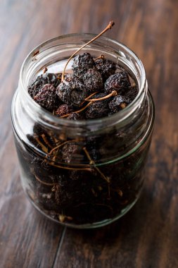 Koyu ahşap yüzeyde yemeye kurutulmuş kiraz hazır kavanoz. Organik gıda.