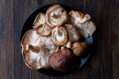 Shiitake mantar koyu ahşap yüzeyinde siyah plaka. Organik gıda.