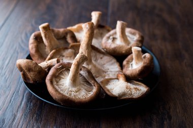 Shiitake mantar koyu ahşap yüzeyinde siyah plaka. Organik gıda.