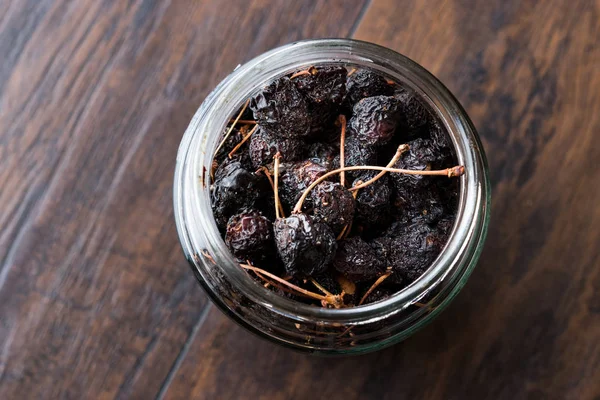 Koyu ahşap yüzeyde yemeye kurutulmuş kiraz hazır kavanoz. Organik gıda.