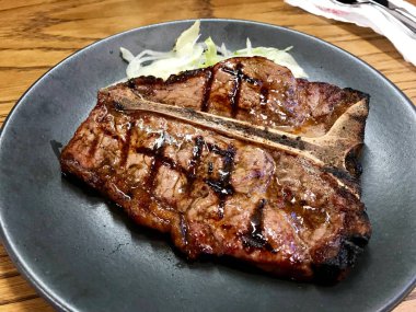 T-Bone biftek Served siyah plaka restoran ızgara. Organik et.