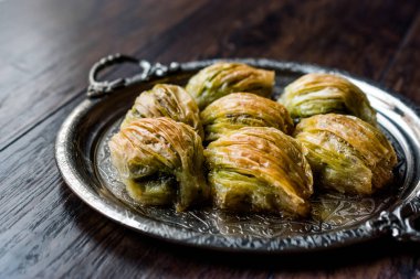 Yeşil fıstık tozu ve gümüş tepsi içinde tereyağı krema ile Türk Midye Baklava (midye şekil Baklawa). Fıstıklı tatlı