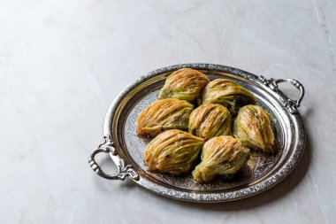 Yeşil fıstık tozu ve gümüş tepsi içinde tereyağı krema ile Türk Midye Baklava (midye şekil Baklawa). Fıstıklı tatlı