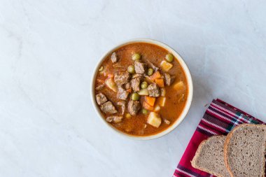 Lezzetli Macar sıcak gulaş çorbası Bograch veya restoranda ahşap yüzeyde bütün tahıl ekmeği ile Gulas kuzu eti güveç. Geleneksel yemekleri. Organik et.