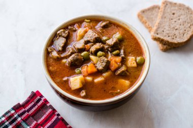 Lezzetli Macar sıcak gulaş çorbası Bograch veya restoranda ahşap yüzeyde bütün tahıl ekmeği ile Gulas kuzu eti güveç. Geleneksel yemekleri. Organik et.