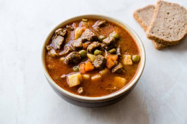 Lezzetli Macar sıcak gulaş çorbası Bograch veya restoranda ahşap yüzeyde bütün tahıl ekmeği ile Gulas kuzu eti güveç. Geleneksel yemekleri. Organik et.